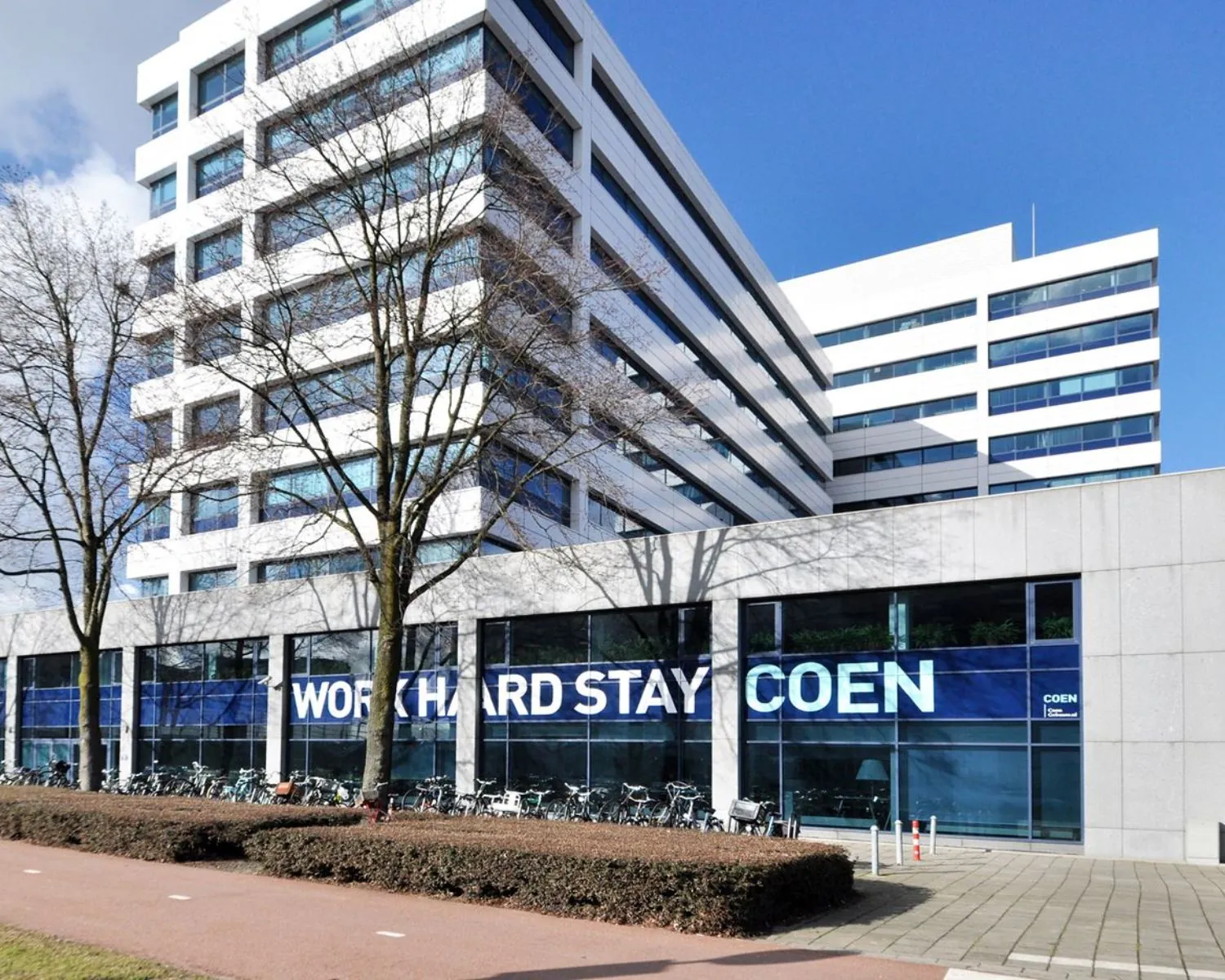 Modern kantoorgebouw Coengebouw aan de Kabelweg 37 in Amsterdam met de tekst "Work Hard Stay Coen" op de gevel.
