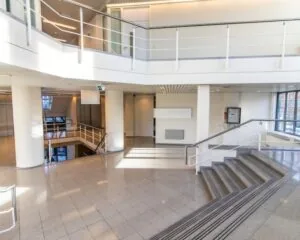 Moderne en lichte entreehal van een kantoorpand aan de Gaetano Martinolaan 75-95 in Maastricht met trappen, balustrades en grote ramen.