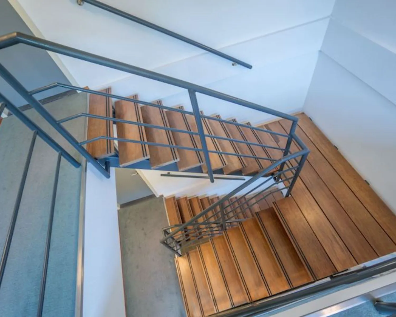 Houten trap met metalen leuning in een modern kantoorpand aan de Reeuwijkse Poort 114.