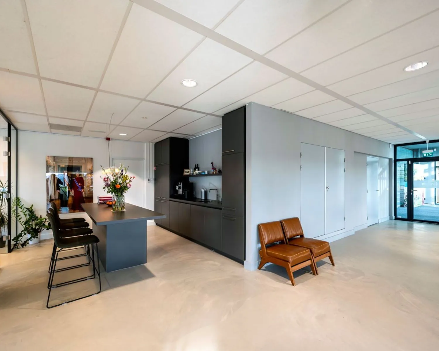 Moderne kantoorruimte aan het Rietlandpark 301 in Amsterdam met open pantry, hoge tafel met barkrukken en een wachtruimte met twee leren stoelen.