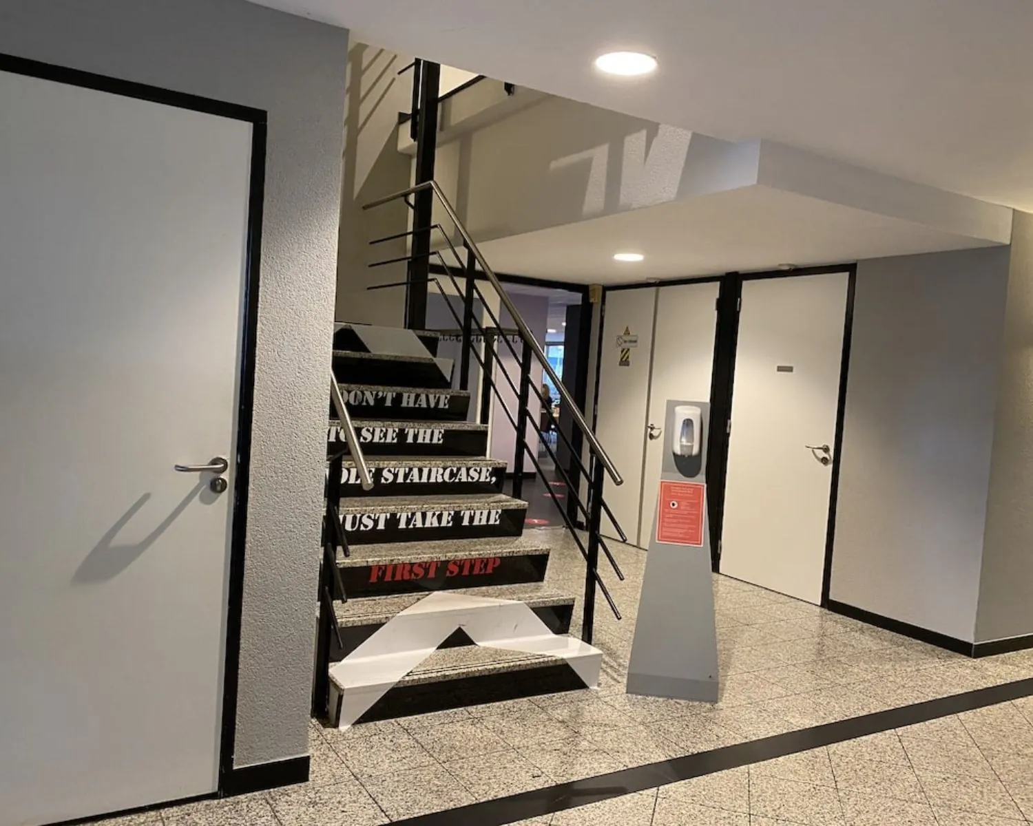 Ingangshal van een kantoorruimte aan de Elisabethhof in Leiderdorp met trap, deuren en desinfectiezuil.