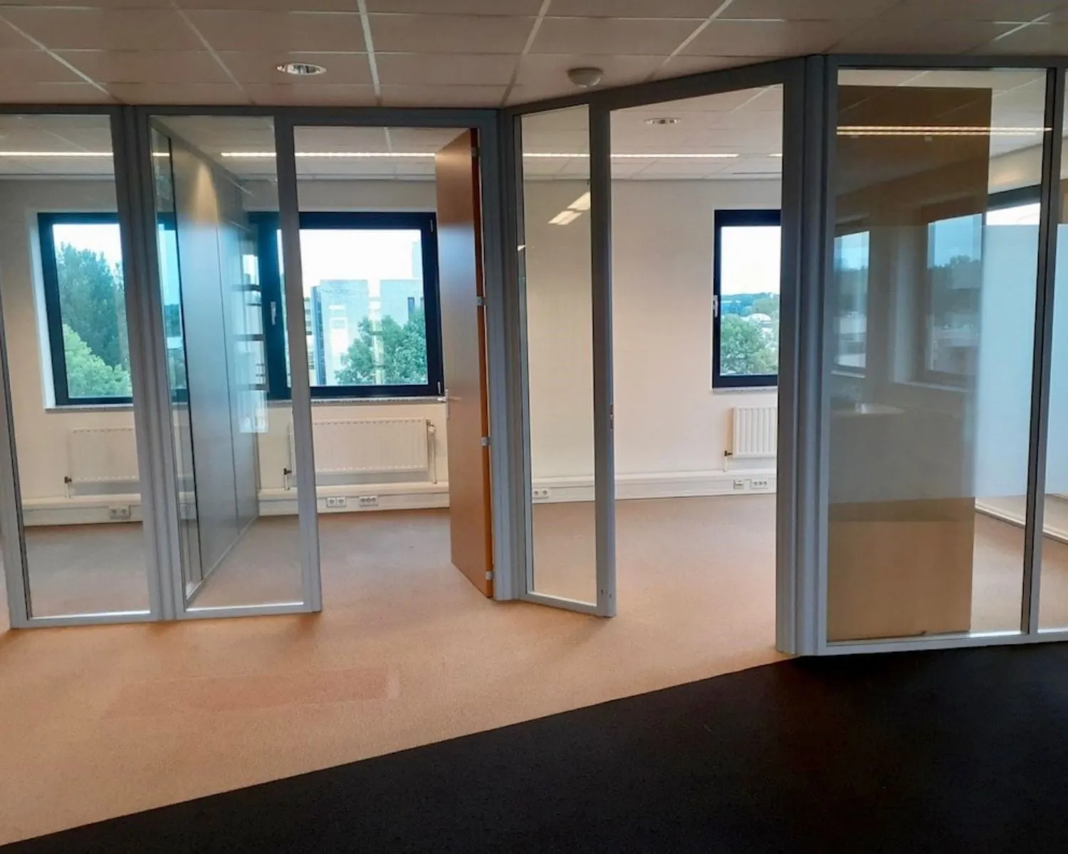 Moderne kantoorruimte met glazen scheidingswanden en uitzicht op groen aan de Hardwareweg in Amersfoort.