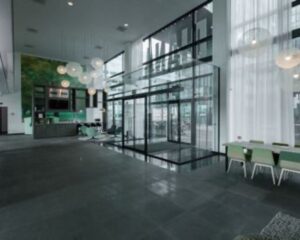 Moderne entreehal van een kantoorgebouw aan de Herikerbergweg 292 in Amsterdam met glazen schuifdeuren, zithoek en koffiebar.
