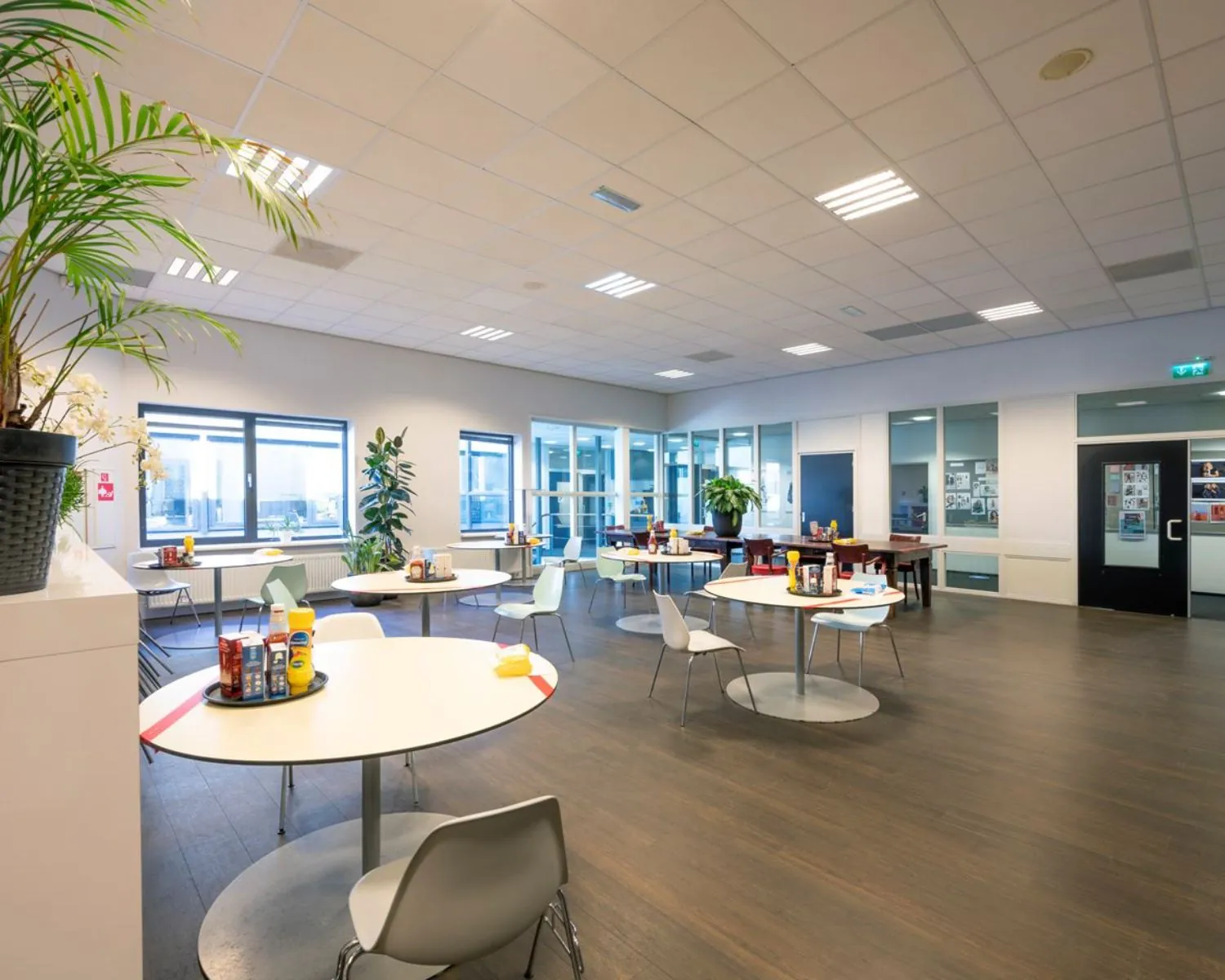 Kantine met ronde tafels en stoelen in een moderne kantoorruimte aan Stammerhove 1 in Diemen.