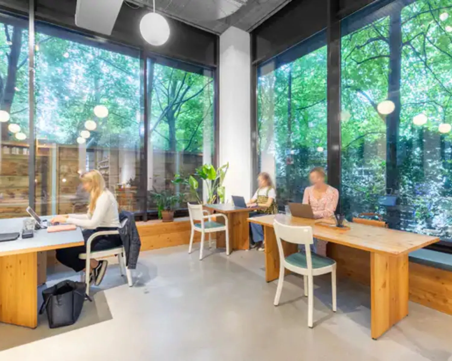 Moderne kantoorruimte aan de Vijzelstraat 60 in Amsterdam met grote ramen, veel daglicht en mensen die aan houten bureaus werken.