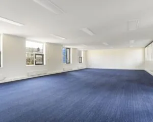 Lichte, ruime kantoorruimte met blauw tapijt aan de Wilhelminastraat 43A in Haarlem.