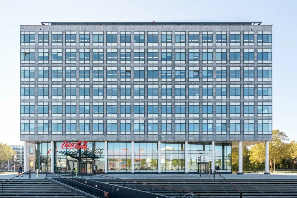 Vooraanzicht van een modern kantoorgebouw aan de Watermanweg met een Coca-Cola-logo boven de ingang.
