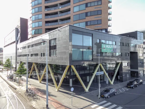 Kantoorgebouw aan het Willemsplein met opvallende gele V-pilaren en een "Te Huur" bord op de gevel.