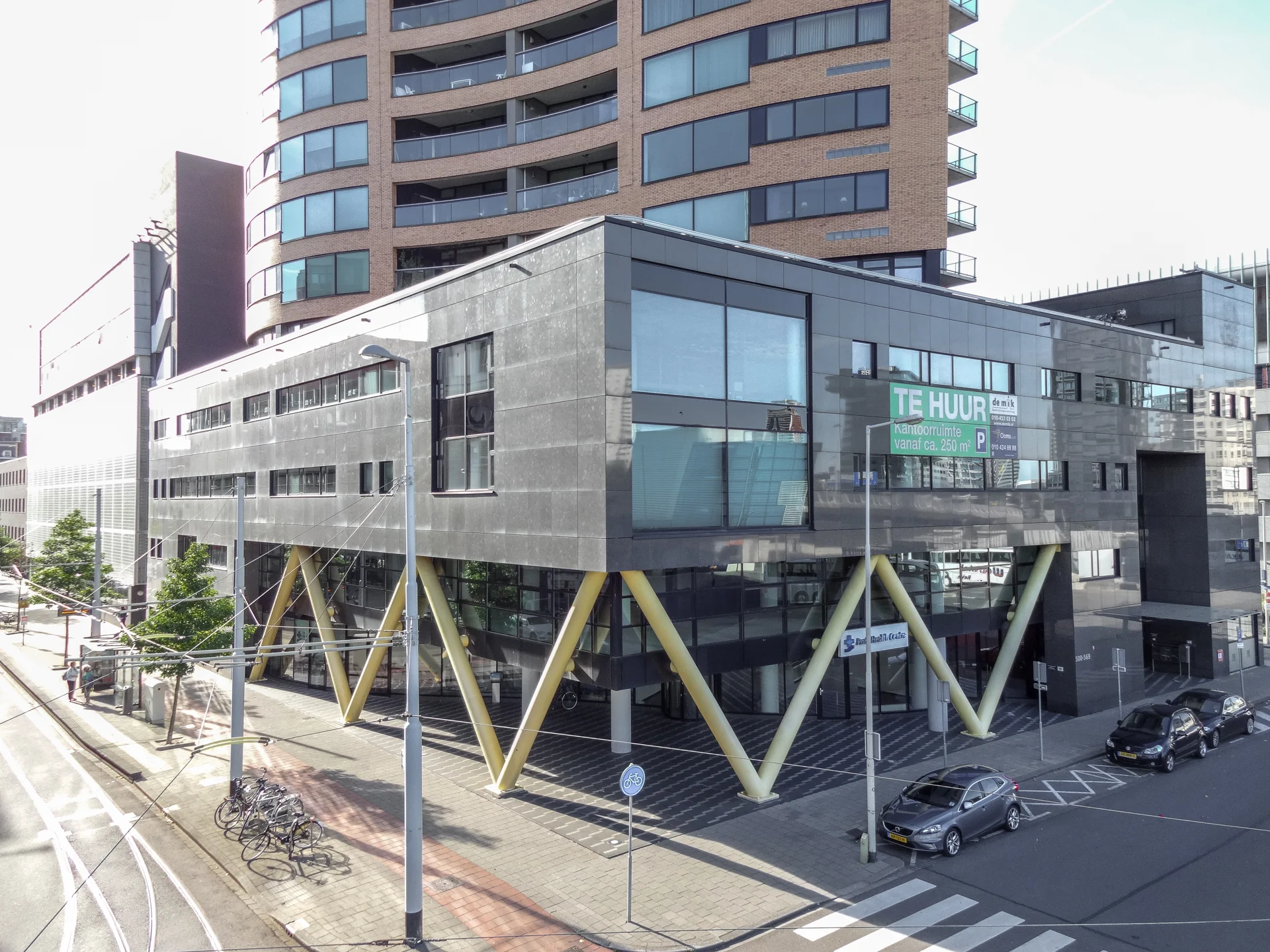 Kantoorgebouw aan het Willemsplein met opvallende gele V-pilaren en een "Te Huur" bord op de gevel.