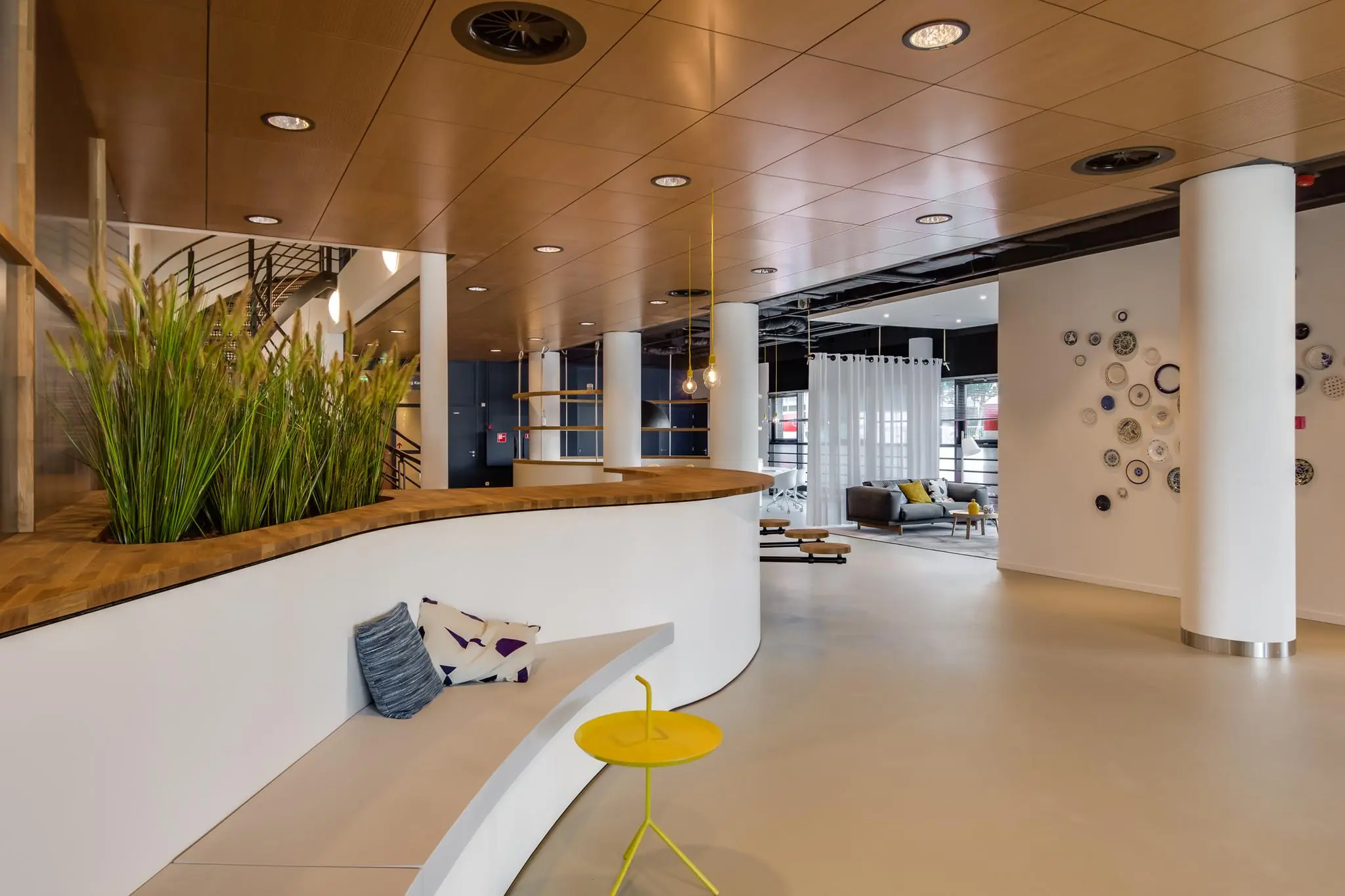 Modern interieur van een kantoorruimte aan het Willemsplein met zithoek, houten plafond en decoratieve wand met borden.