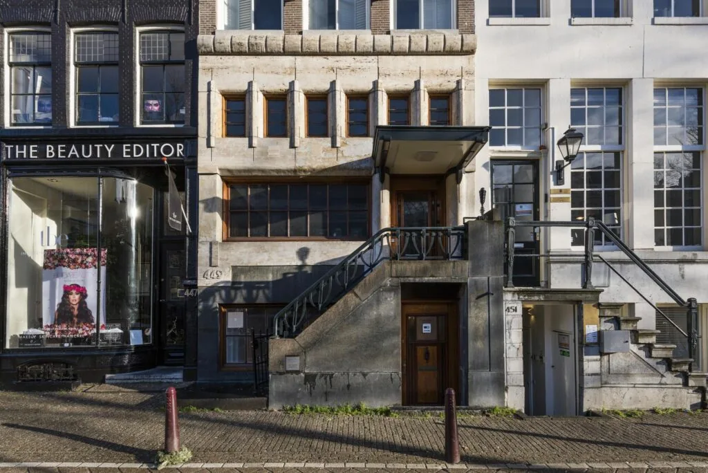 Gevels van drie panden aan de Herengracht in Amsterdam met huisnummers 447, 449 en 451, waaronder een beautysalon en een entree met trap.