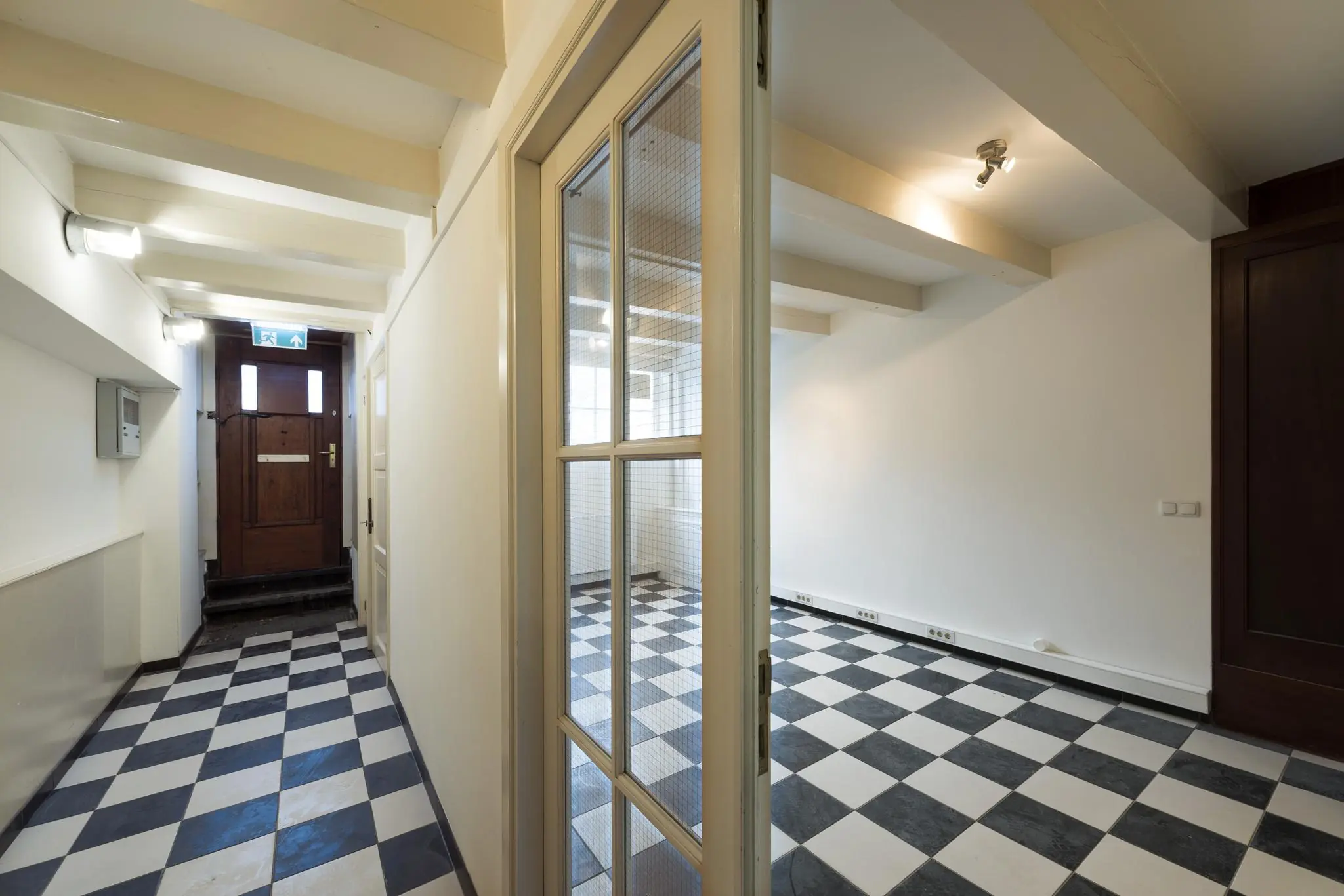 Hal met zwart-wit geblokte tegelvloer en houten voordeur aan de Herengracht.