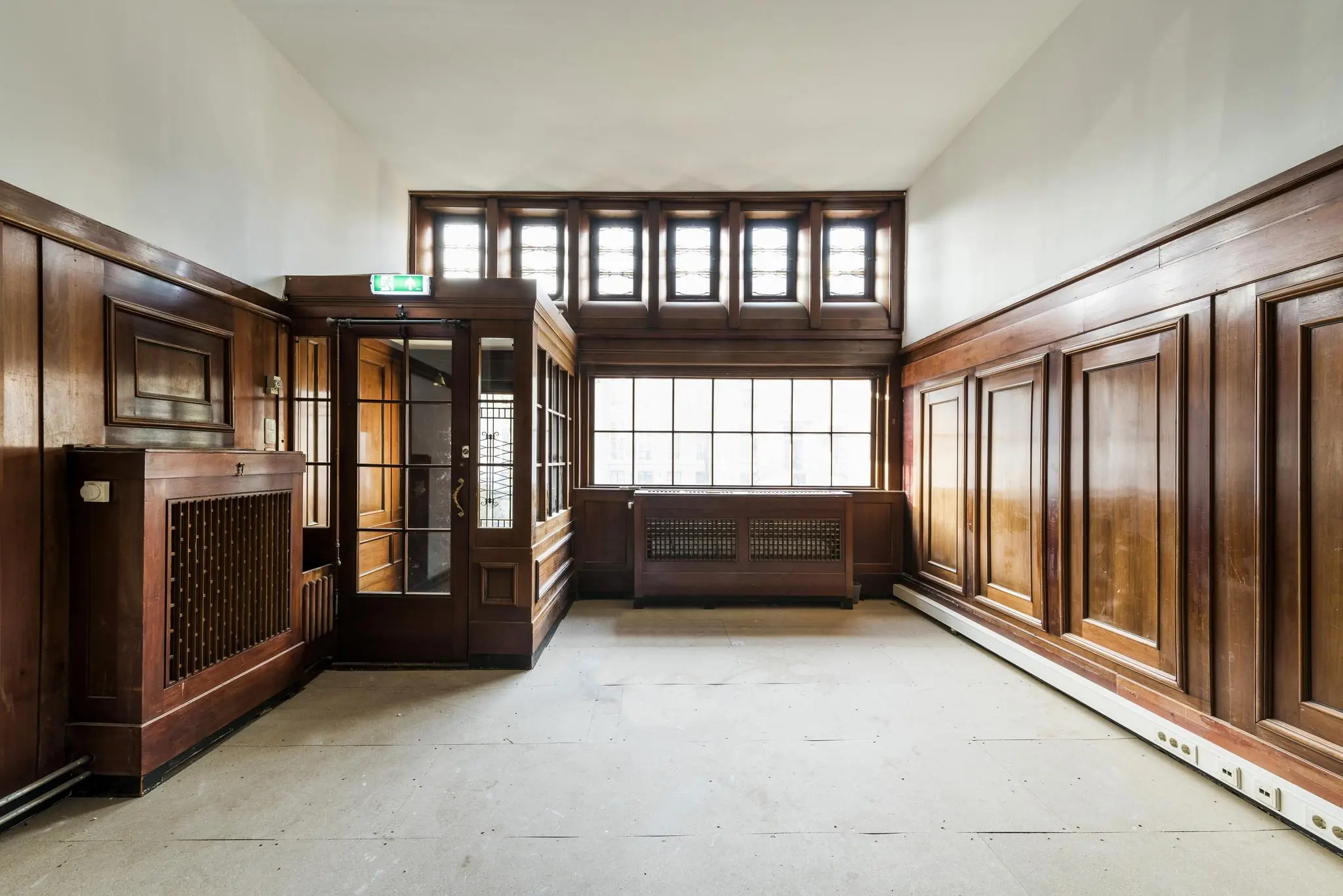 Lichte kamer met houten lambrisering en glas-in-loodramen in een historisch pand aan de Herengracht.