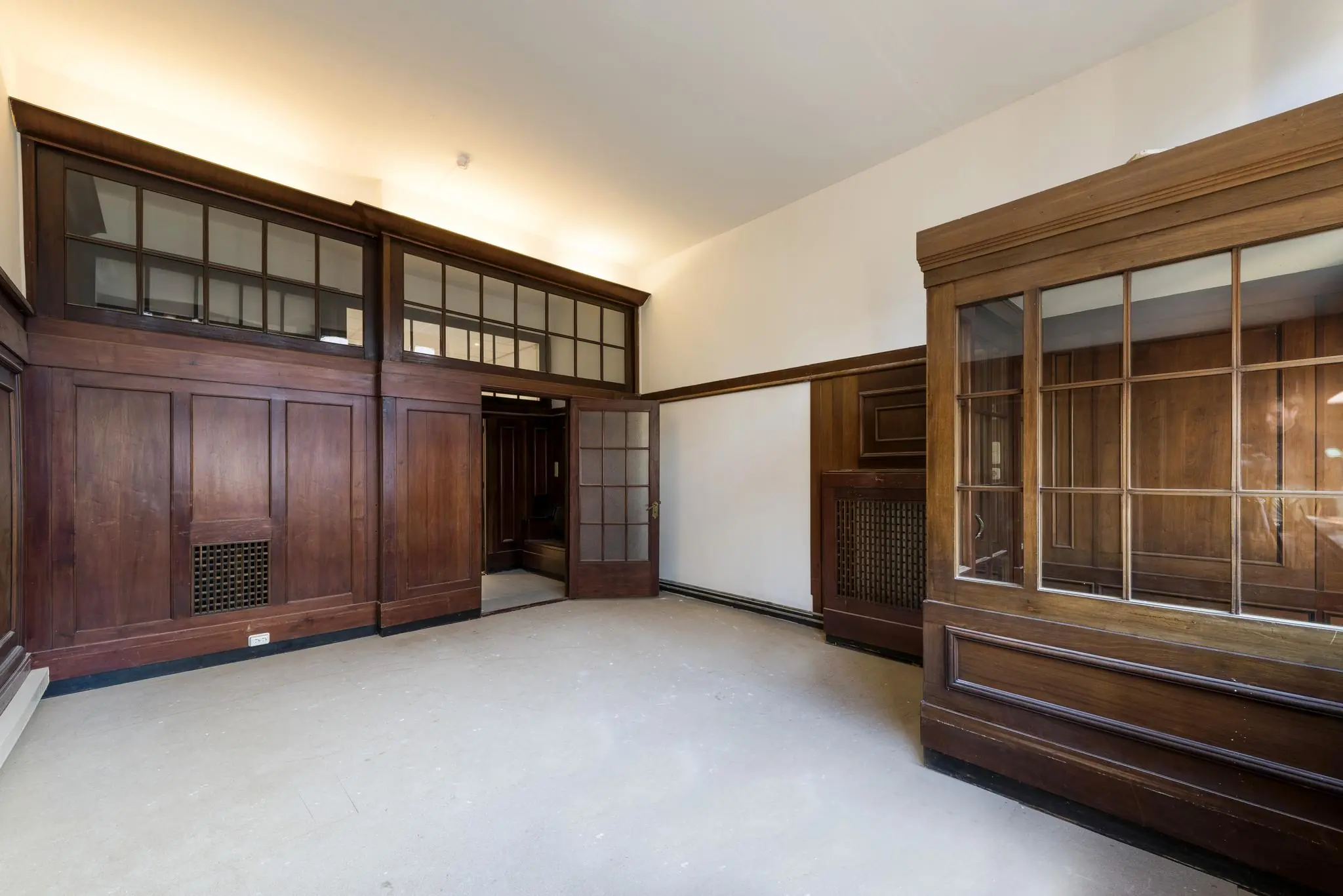 Lege kamer aan de Herengracht met karakteristieke houten lambrisering en glazen scheidingswanden.