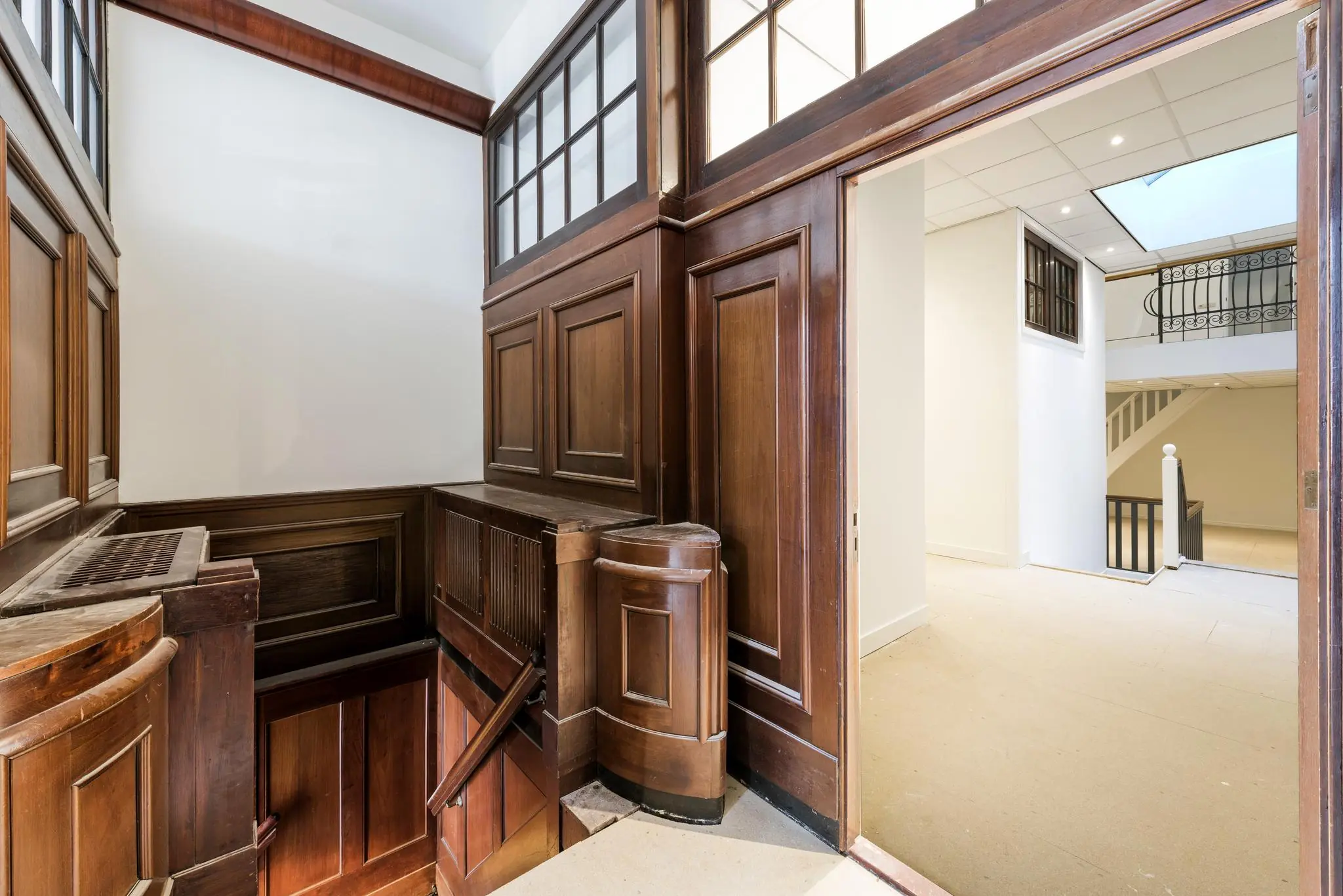 Historisch houten trappenhuis met klassieke lambrisering en doorgang naar een modernere, lichte ruimte in een pand aan de Herengracht.