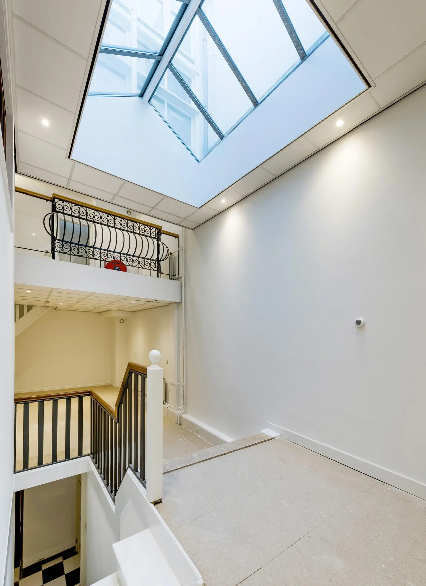 Licht trappenhuis in een pand aan de Herengracht met glazen dak en smeedijzeren balustrade.