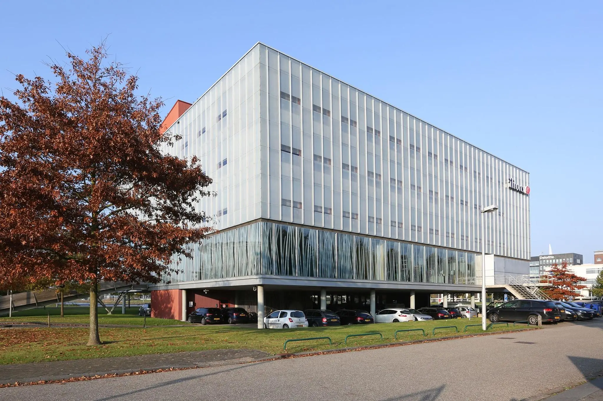 Modern kantoorgebouw aan de Hondiuslaan met parkeergarage en herfstkleurige bomen op de voorgrond.