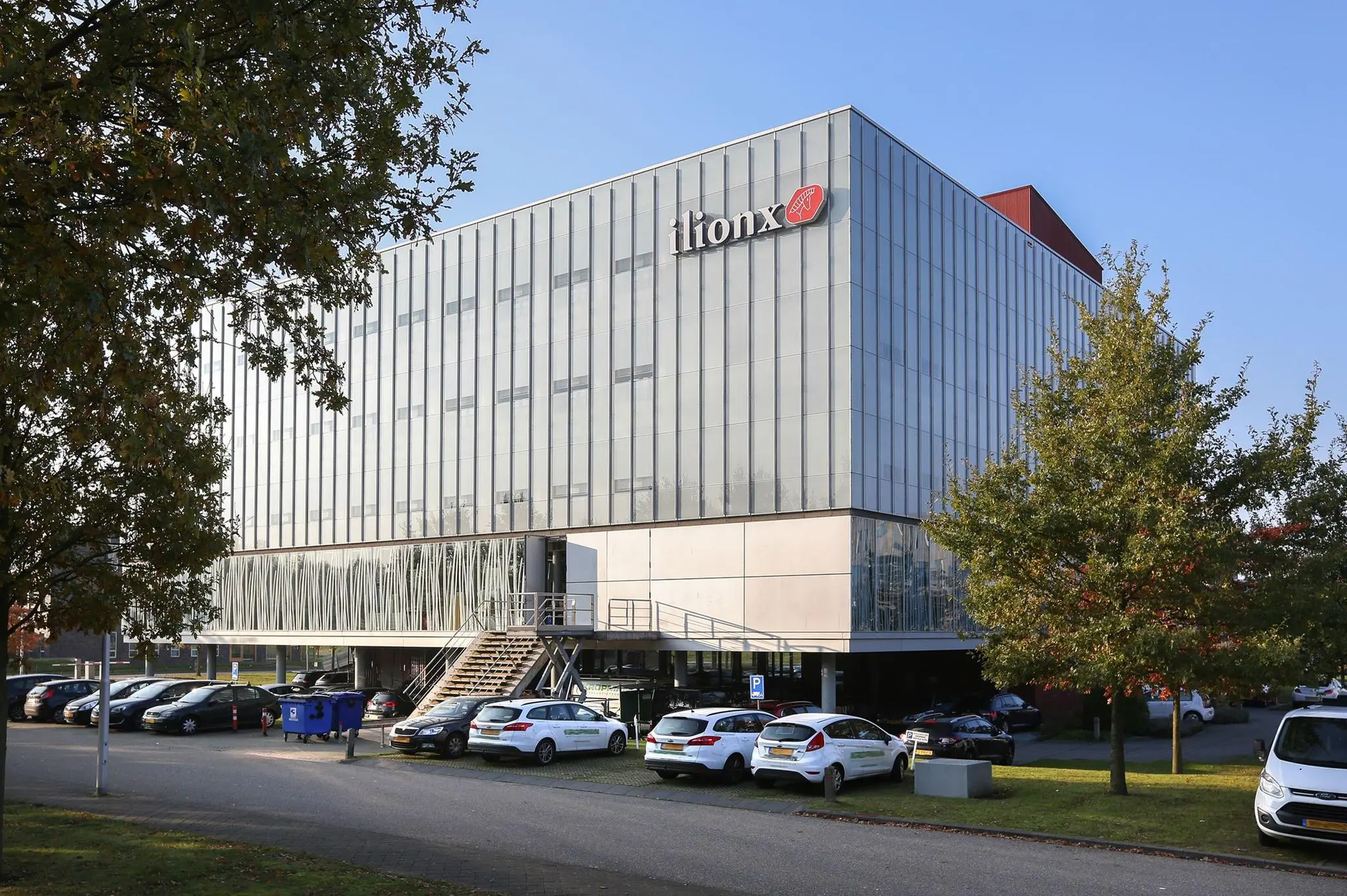Modern kantoorgebouw van ilionx aan de Hondiuslaan met geparkeerde auto's op de voorgrond.