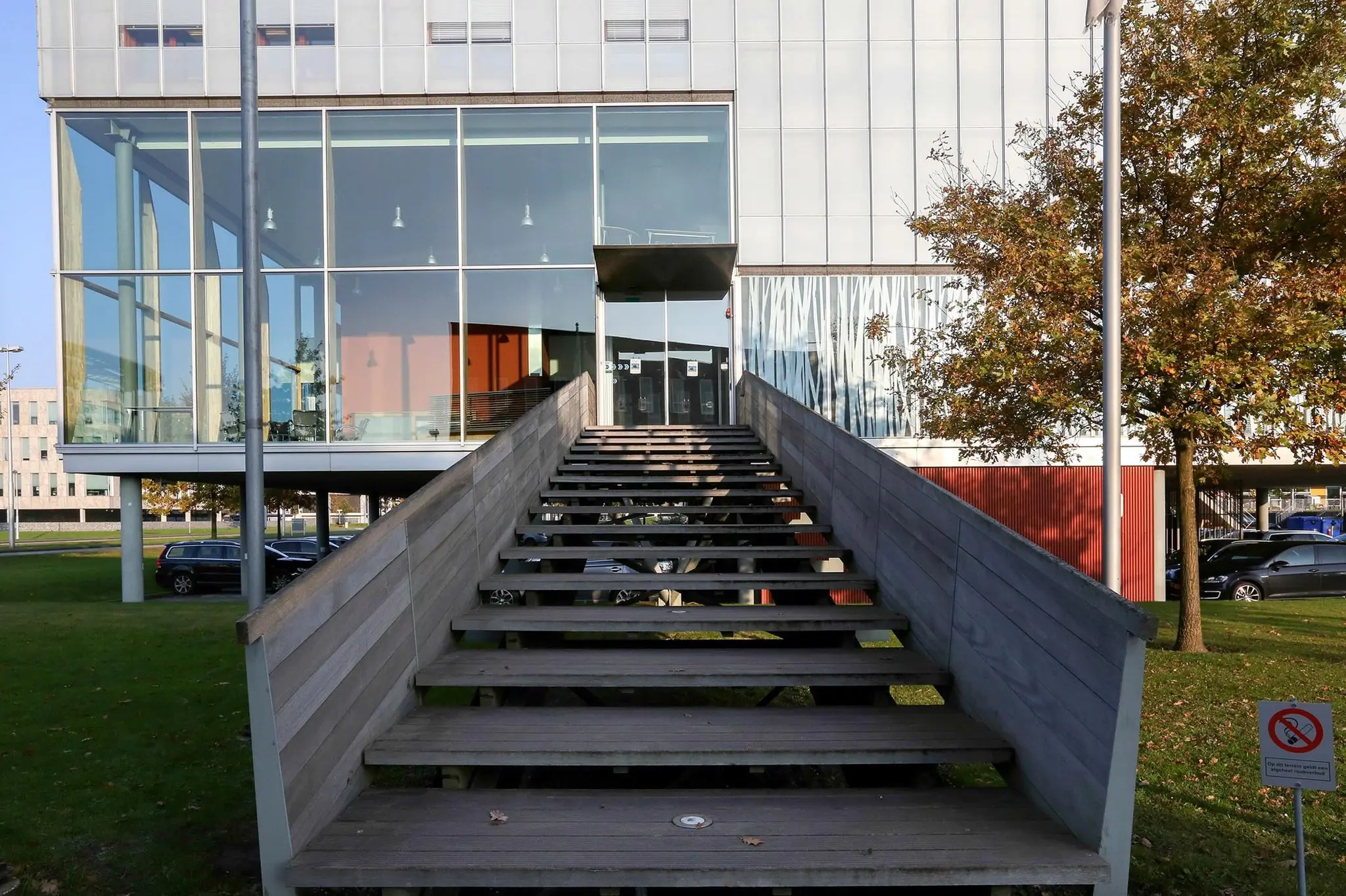 Houten trap leidt naar glazen entree van modern kantoorgebouw aan de Hondiuslaan.