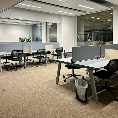 Een moderne, lege kantoorruimte met meerdere werkplekken en bureaustoelen.