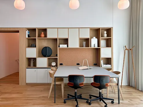 Een moderne vergaderruimte met een tafel, stoelen en een ingebouwde wandkast.