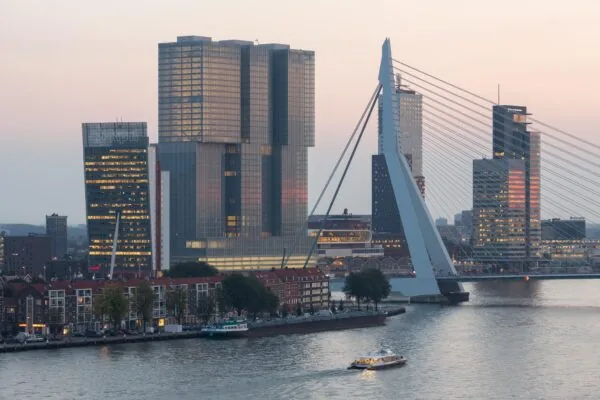 Skyline van Rotterdam bij zonsondergang met de Wilhelminakade, De Rotterdam en de Erasmusbrug.