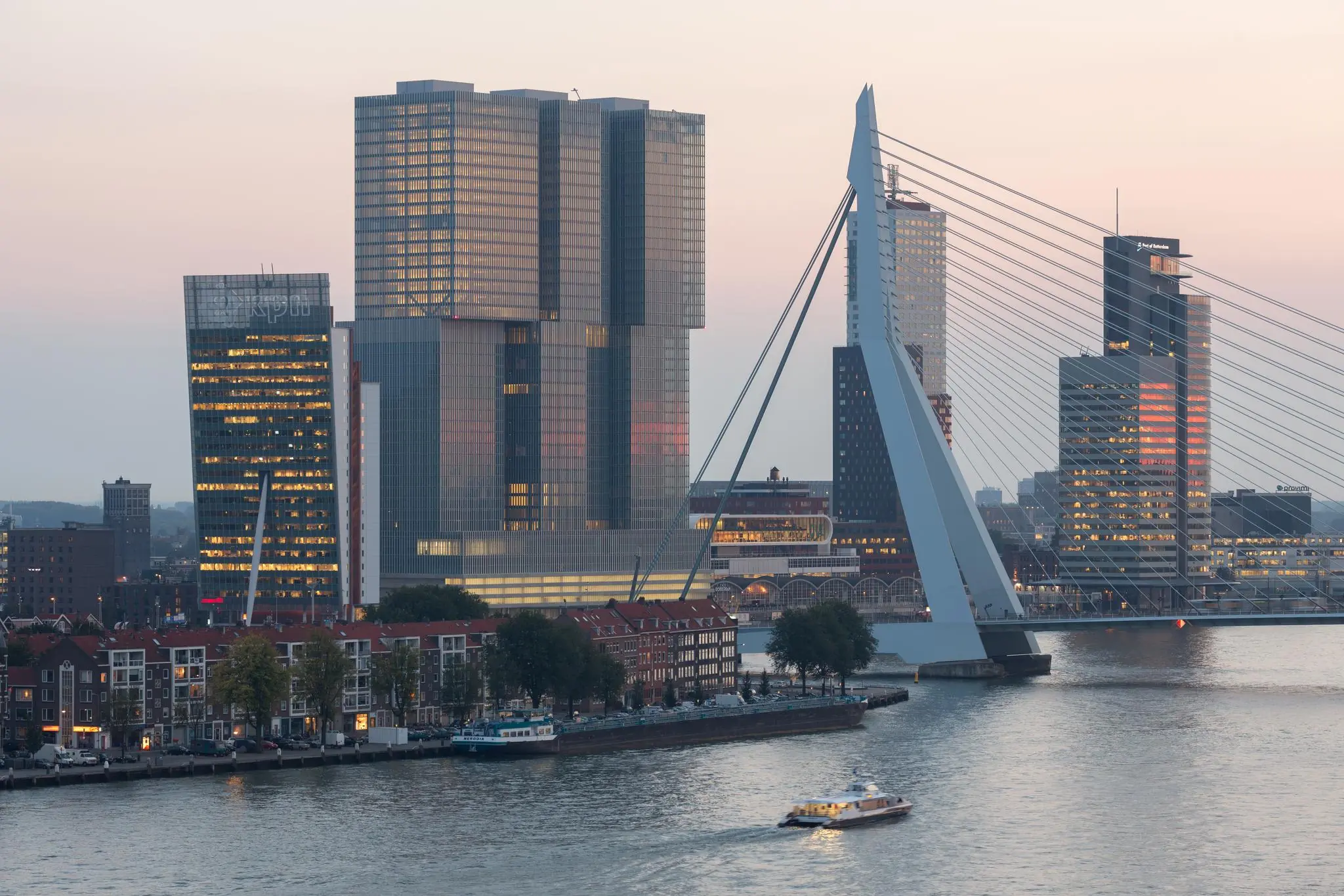 Skyline van Rotterdam bij zonsondergang met de Wilhelminakade, De Rotterdam en de Erasmusbrug.