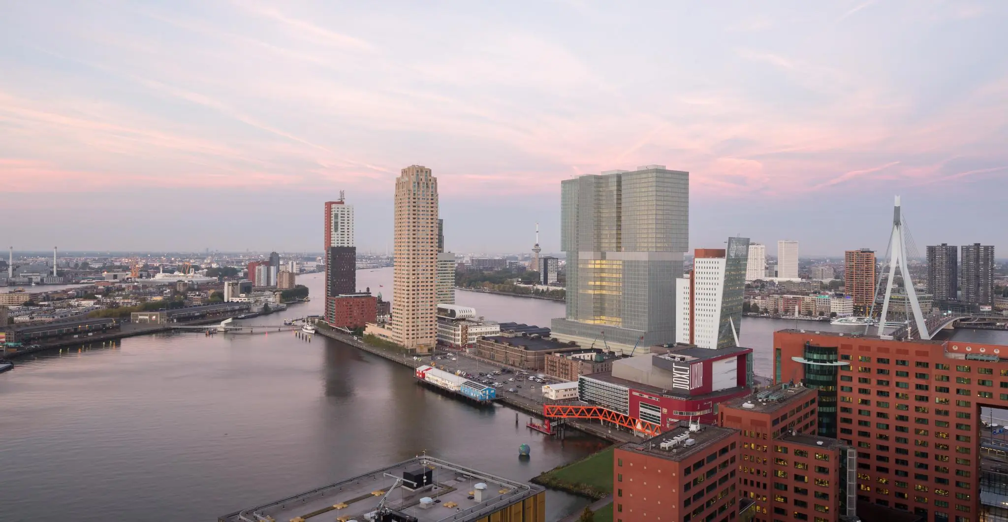 Skyline van Rotterdam met de Wilhelminakade, De Rotterdam en de Erasmusbrug bij zonsondergang.