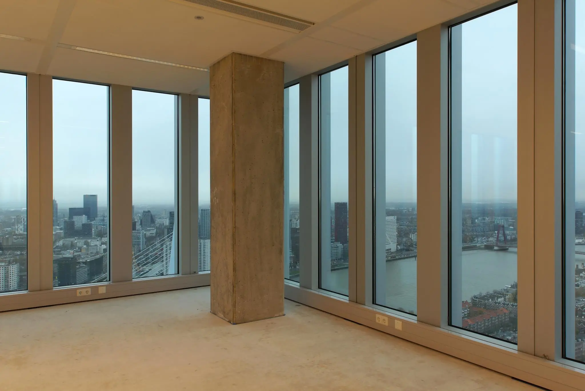 Uitzicht vanuit een leegstaande kantoorruimte aan de Wilhelminakade op de skyline van Rotterdam en de Willemsbrug.