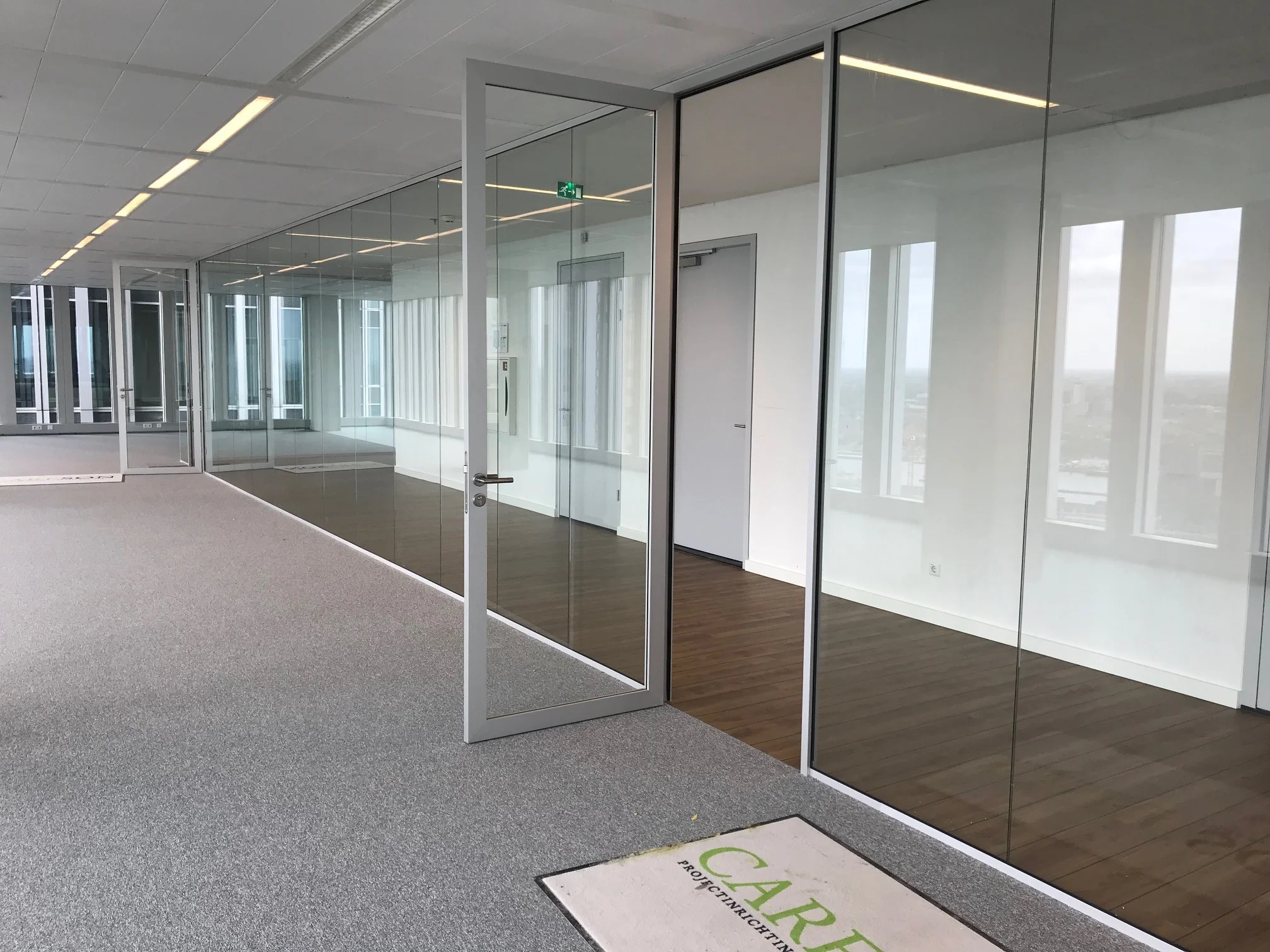 Modern kantoorinterieur aan de Wilhelminakade met glazen wanden, tapijtvloer en uitzicht op de stad.