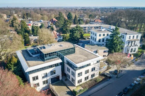 Luchtfoto van het kantoorgebouw Parkstaete aan de Amalialaan, omringd door bomen en naastgelegen panden.
