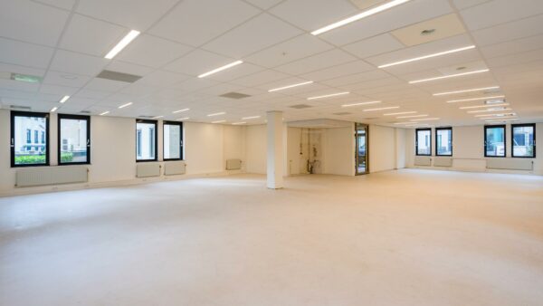 Leeg kantoorpand aan de Amaliastraat met witte muren, systeemplafond en grote ramen.
