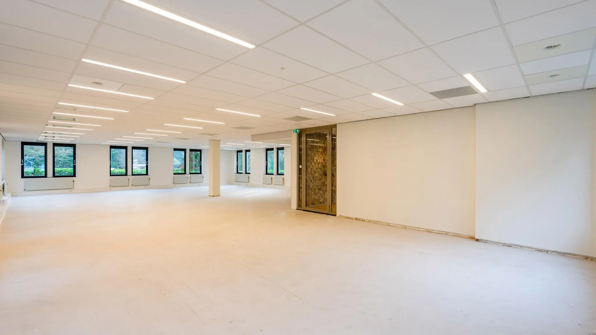 Licht en ruim leeg kantoorpand aan de Amalialaan met systeemplafond en grote ramen.
