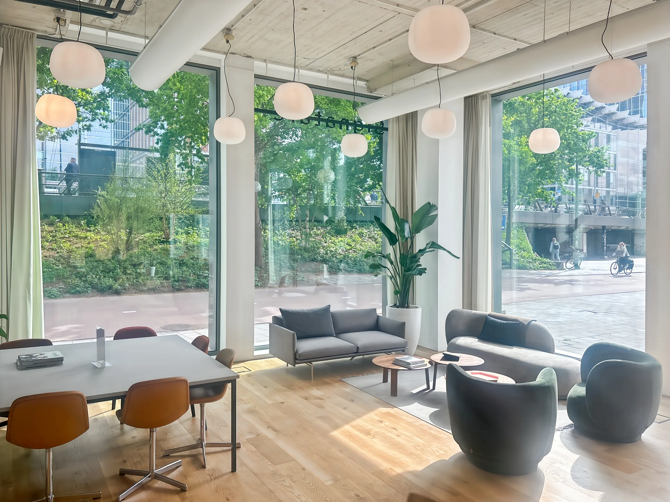 Moderne, lichte kantoorruimte met grote ramen, houten vloer en stijlvolle meubels.