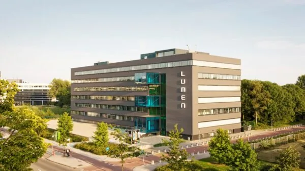 Modern kantoorgebouw Lumen aan de Vlaardingenlaan in Amsterdam, omringd door groen en infrastructuur.