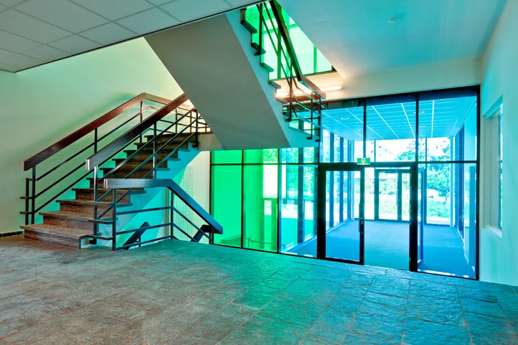 Moderne entreehal van een kantoorgebouw aan de Vlaardingenlaan met een stalen trap en gekleurd glas.