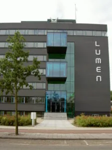 Voorgevel van het moderne kantoorgebouw Lumen aan de Vlaardingenlaan met opvallende blauwe glazen elementen.