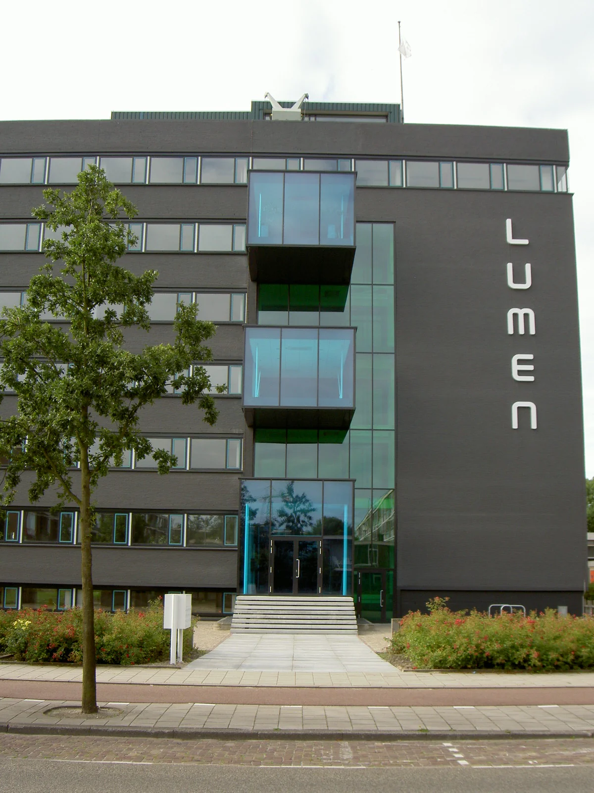 Voorgevel van het moderne kantoorgebouw Lumen aan de Vlaardingenlaan met opvallende blauwe glazen elementen.