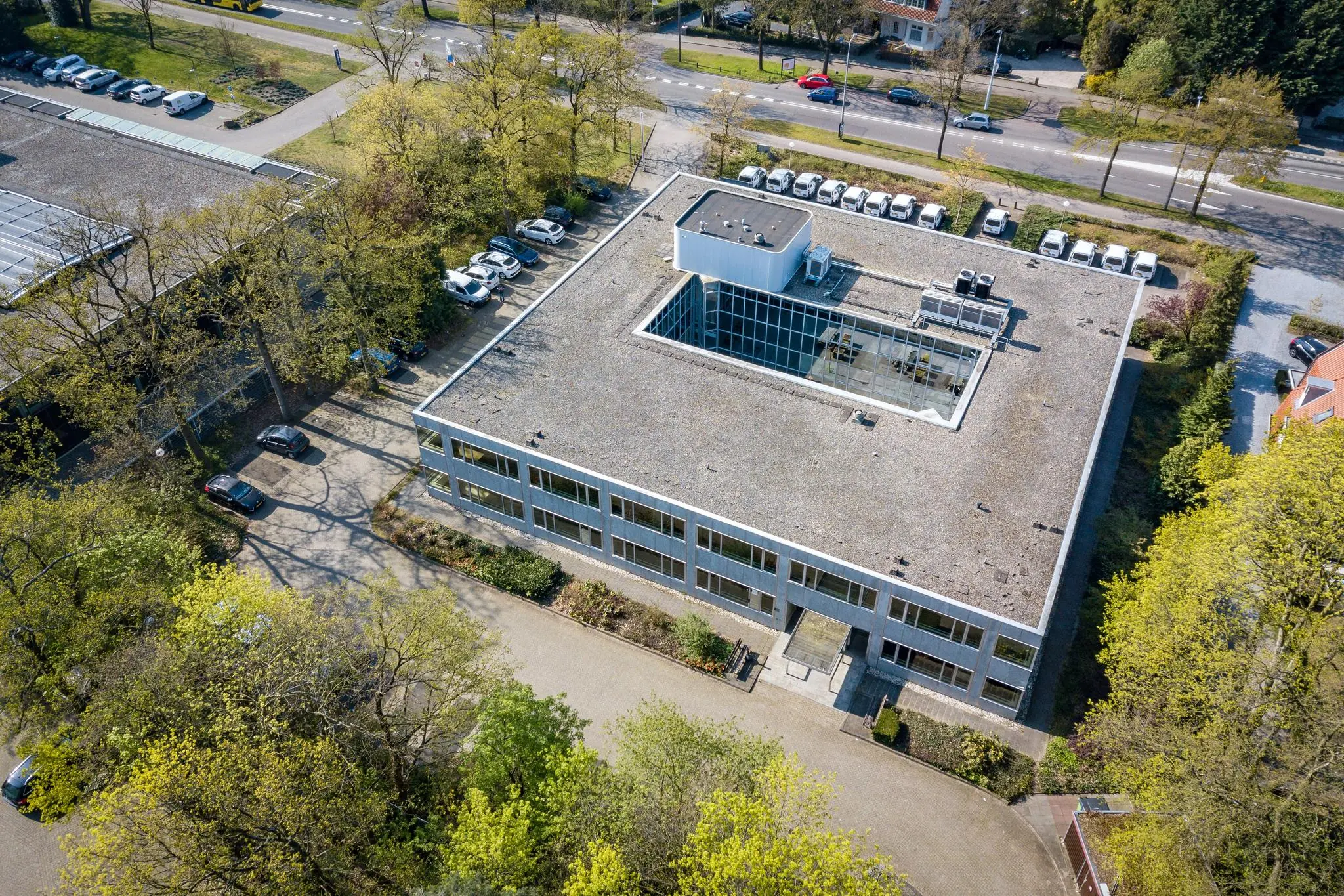 Luchtfoto van een kantoorgebouw aan de Utrechtseweg met een binnenhof en omliggende parkeerplaatsen en bomen.