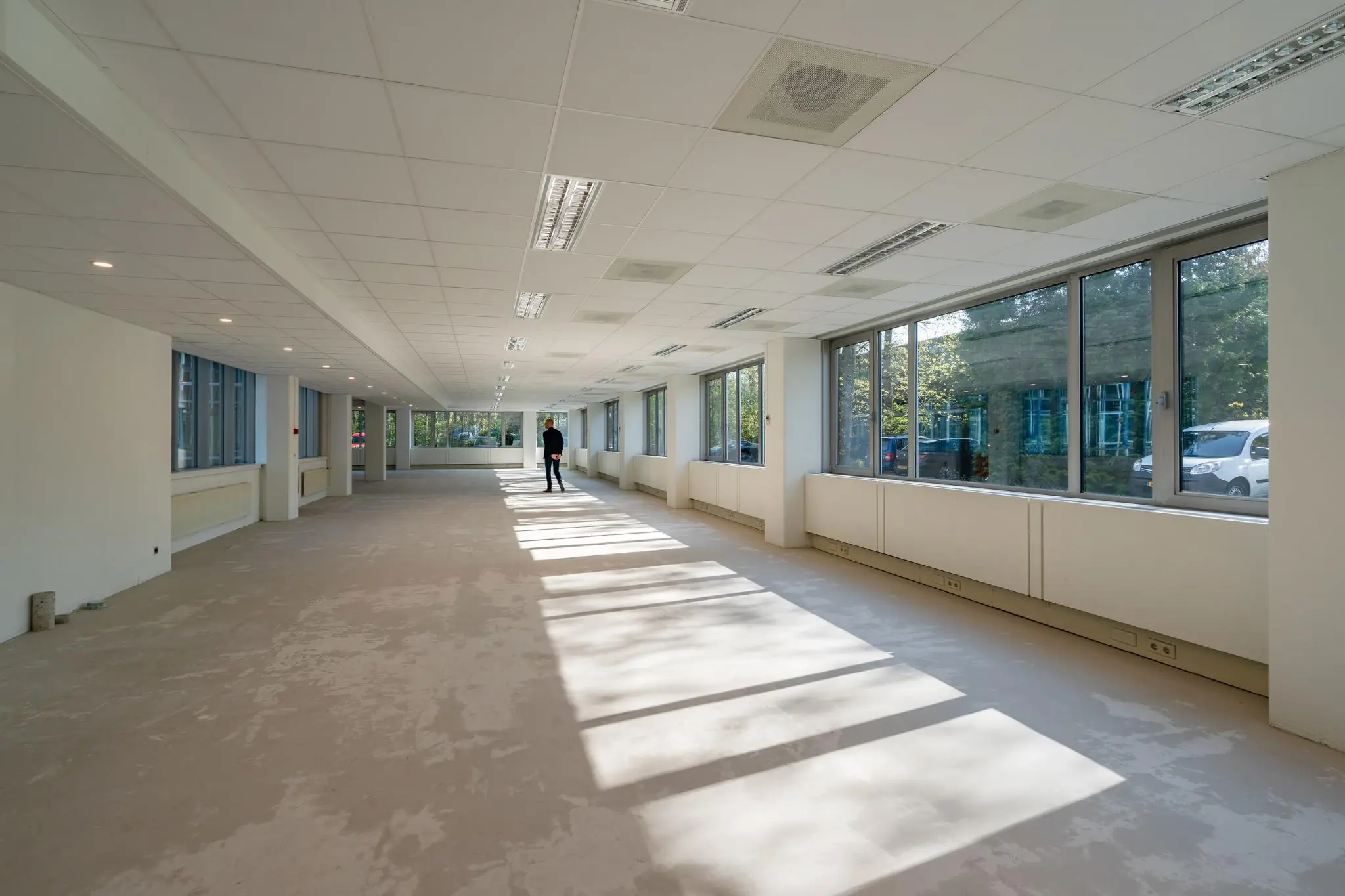 Leegstaand kantoorpand aan de Utrechtseweg met grote ramen en een persoon in de verte.