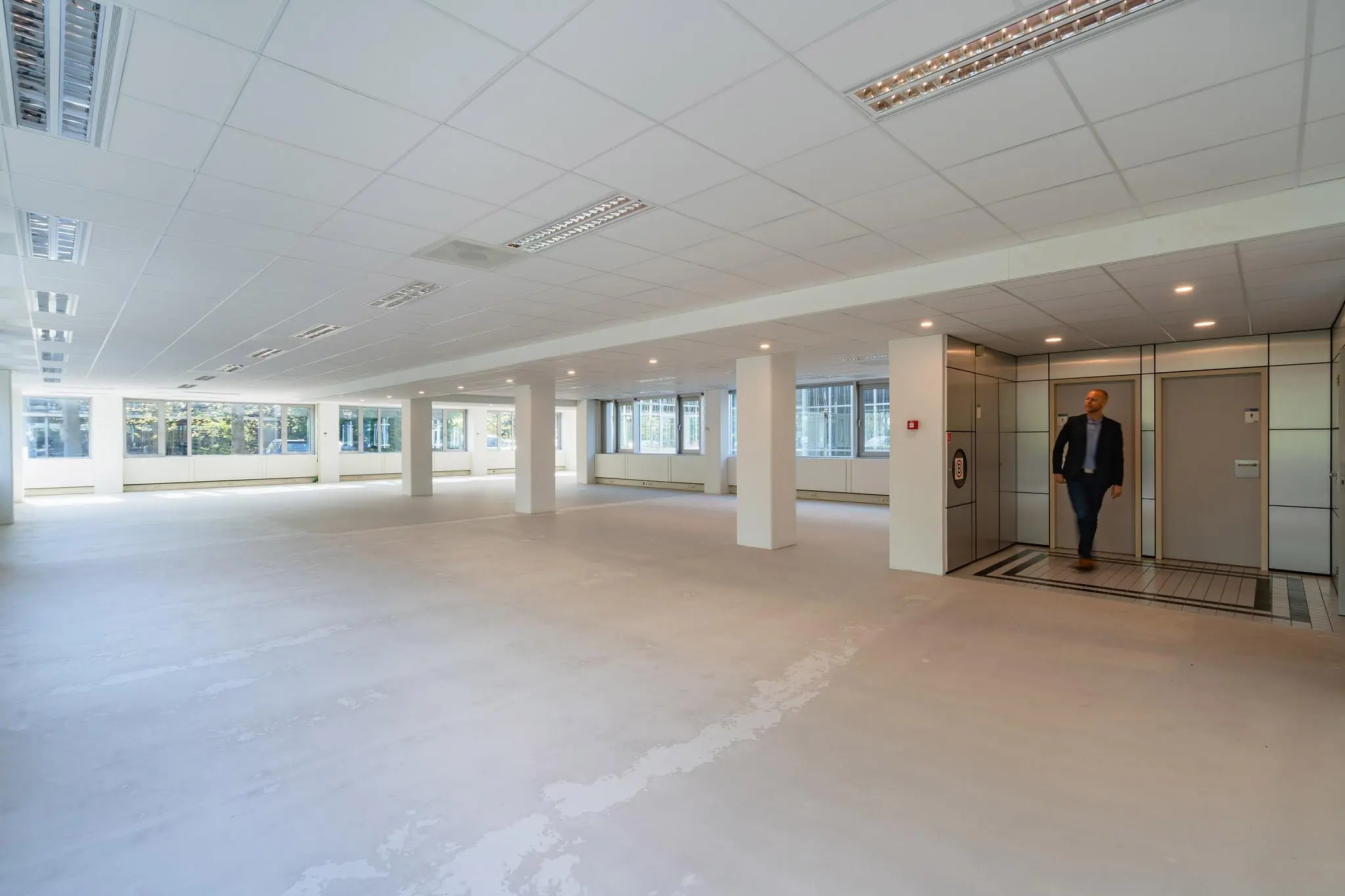 Leeg en licht kantoorpand aan de Utrechtseweg met een man die uit de lift stapt.