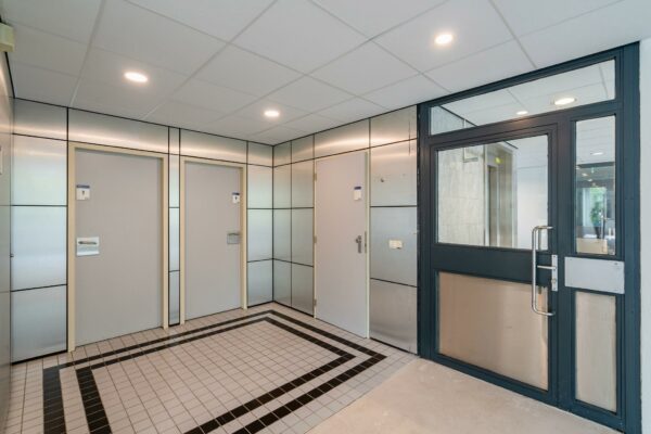 Ingang van een modern kantoorpand aan de Utrechtseweg met drie grijze deuren en een glazen toegangsdeur.