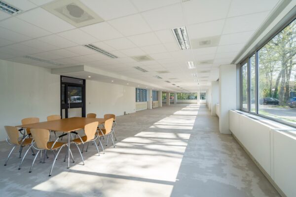 Licht en ruim kantoorpand aan de Utrechtseweg met grote ramen en een vergadertafel met stoelen.