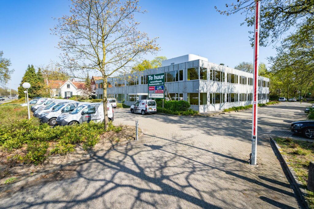 Kantoorgebouw aan de Utrechtseweg te huur met parkeerplaatsen en bedrijfsauto’s op de voorgrond.