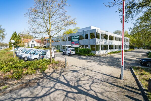 Kantoorgebouw aan de Utrechtseweg te huur met parkeerplaatsen en bedrijfsauto’s op de voorgrond.