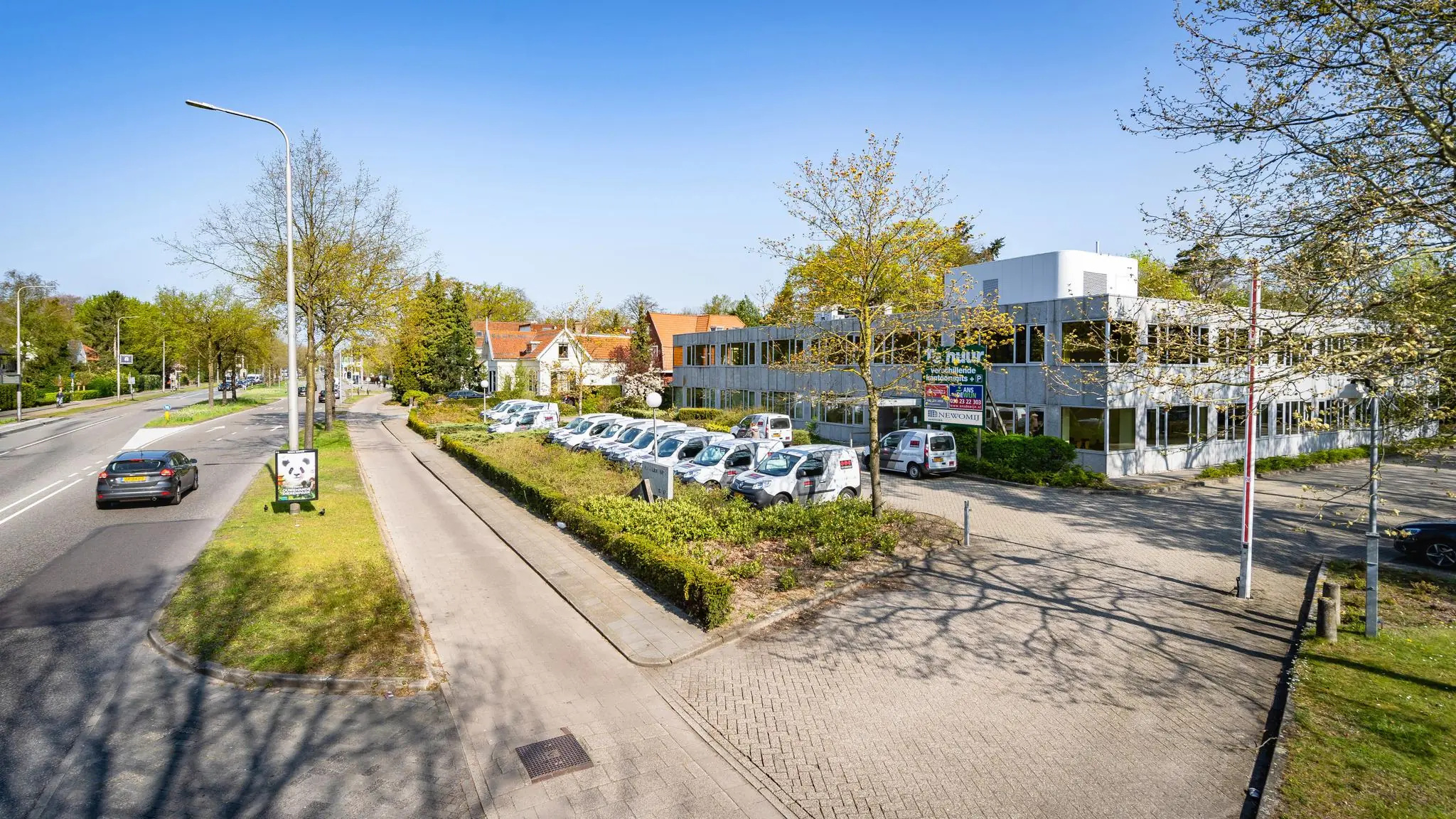 Kantoorpand aan de Utrechtseweg in een groene omgeving met geparkeerde bedrijfsauto’s en langsrijdend verkeer.