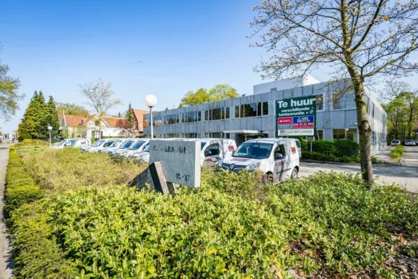 Kantoorpand aan de Utrechtseweg in Zeist met een 'Te huur' bord en geparkeerde bedrijfswagens op de voorgrond.
