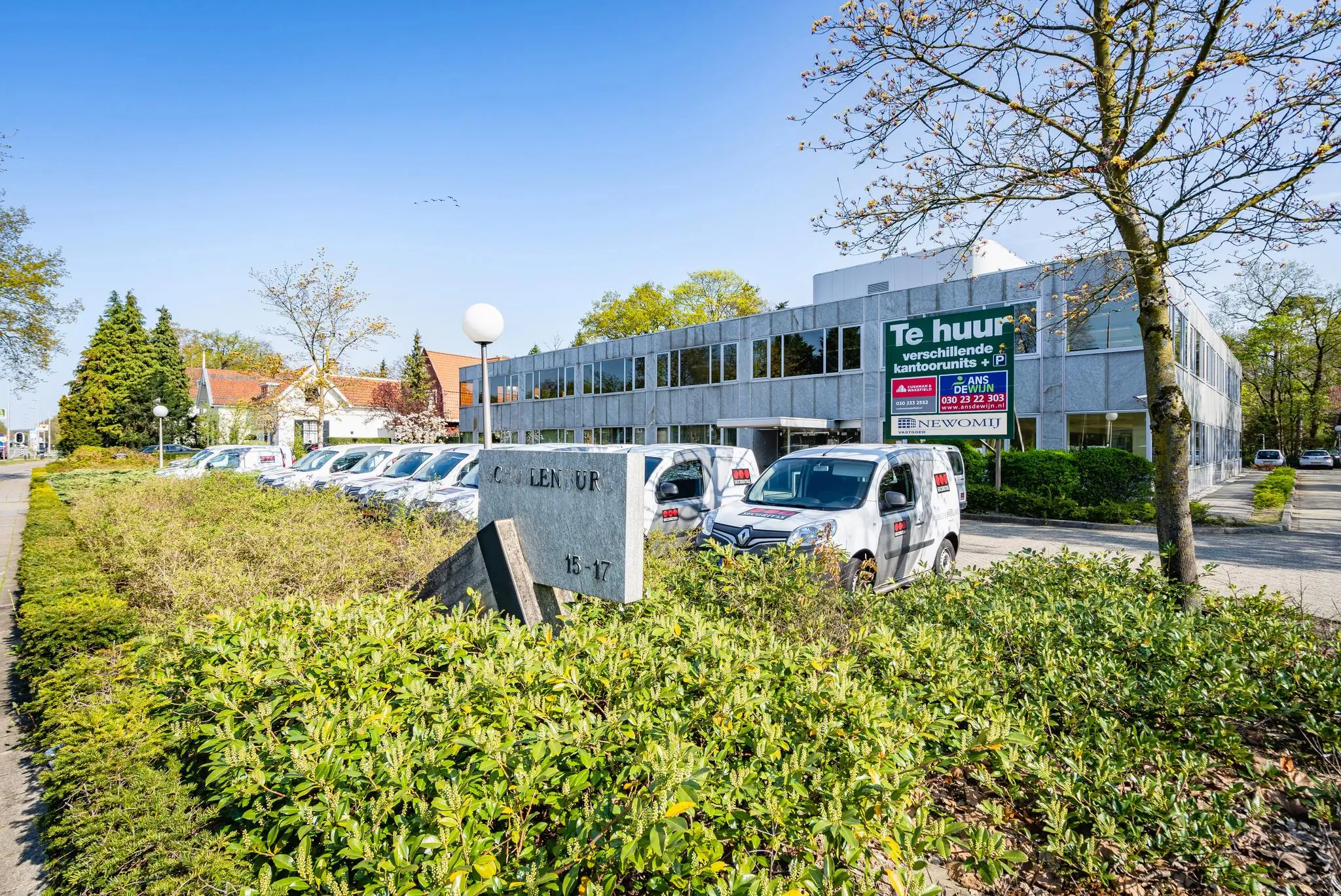 Kantoorpand aan de Utrechtseweg in Zeist met een 'Te huur' bord en geparkeerde bedrijfswagens op de voorgrond.