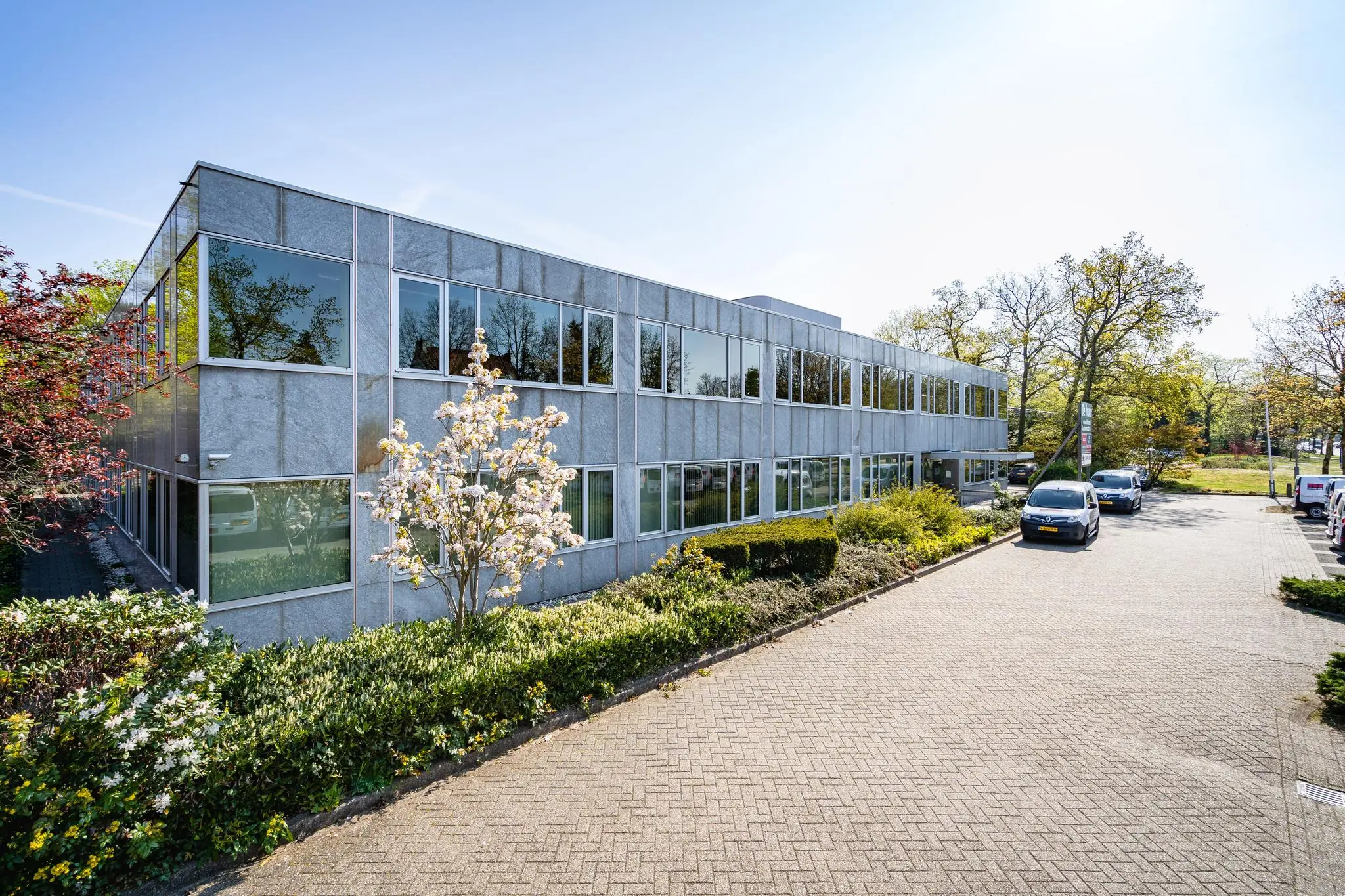 Twee verdiepingen tellend kantoorgebouw aan de Utrechtseweg met parkeerplaatsen en omliggend groen.