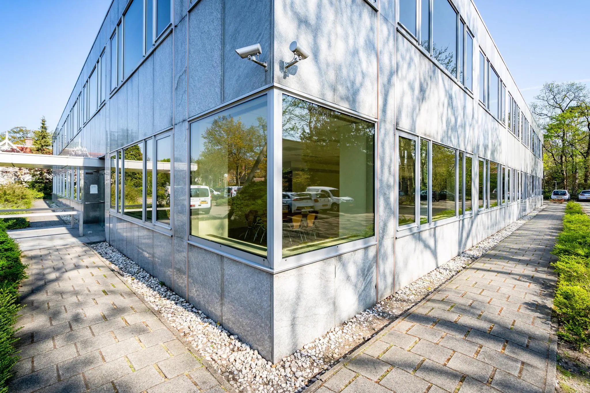 Modern kantoorgebouw aan de Utrechtseweg met grote ramen en omliggende bestrating en groen.